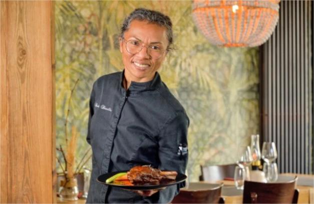Claudia en cuisine, présentant une assiette dans la salle du Bistrot