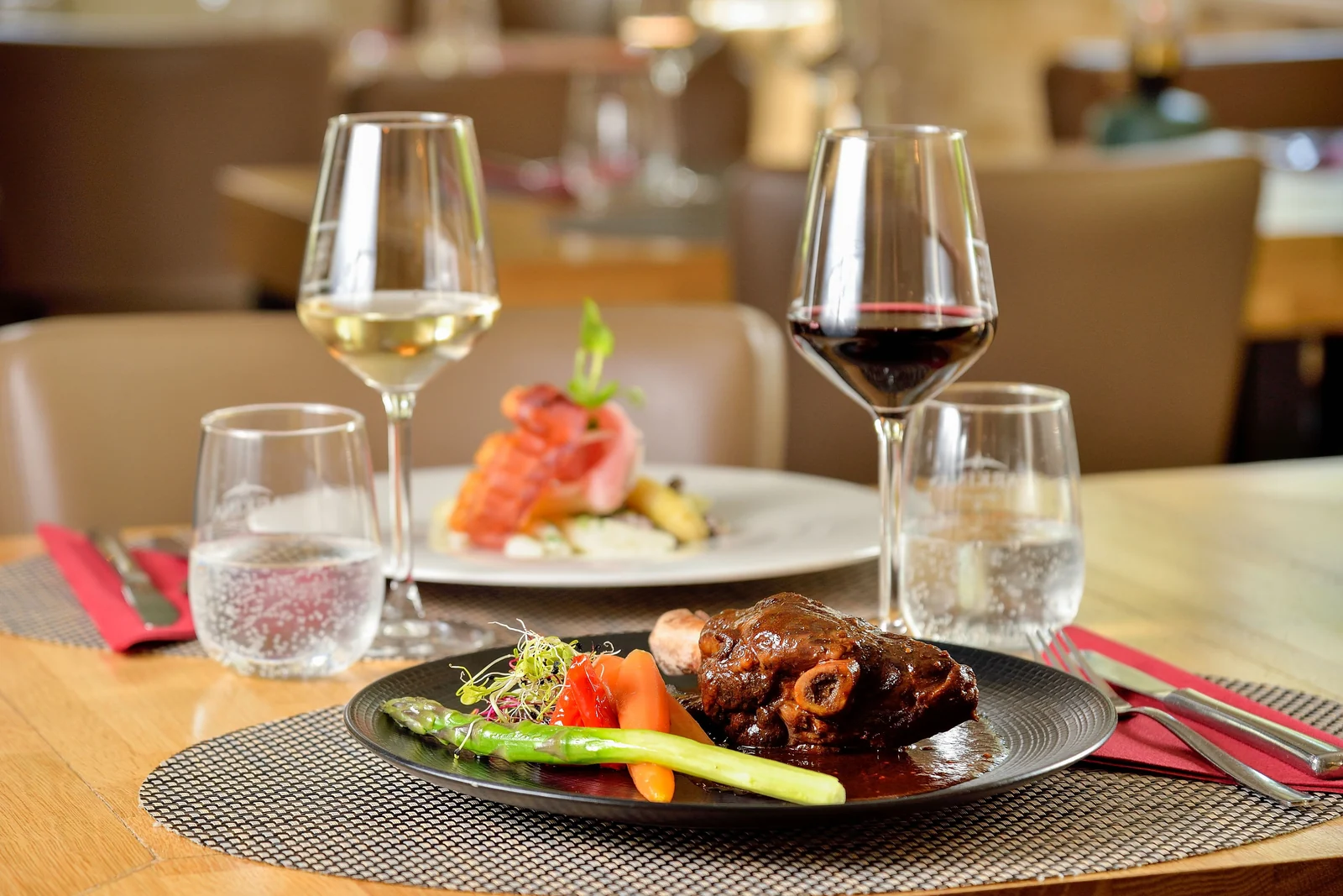 Deux assiettes servies à table au Bistrot, accompagnées de verres de vin